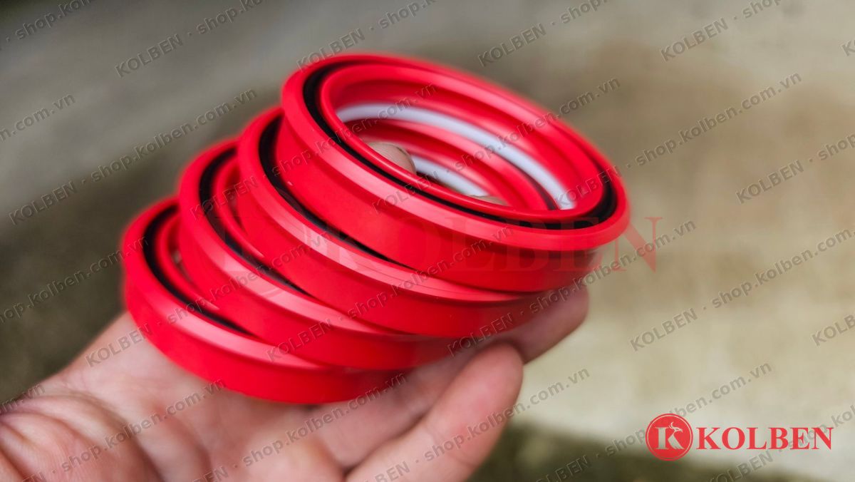 Phớt PU màu đỏ KOLBEN có vòng đệm trắng và O-ring đen, cầm trên tay